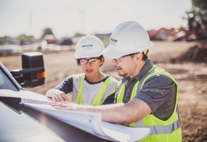 Two Braun Intertec employees wearing hard hats and working together to provide reliable engineering solutions